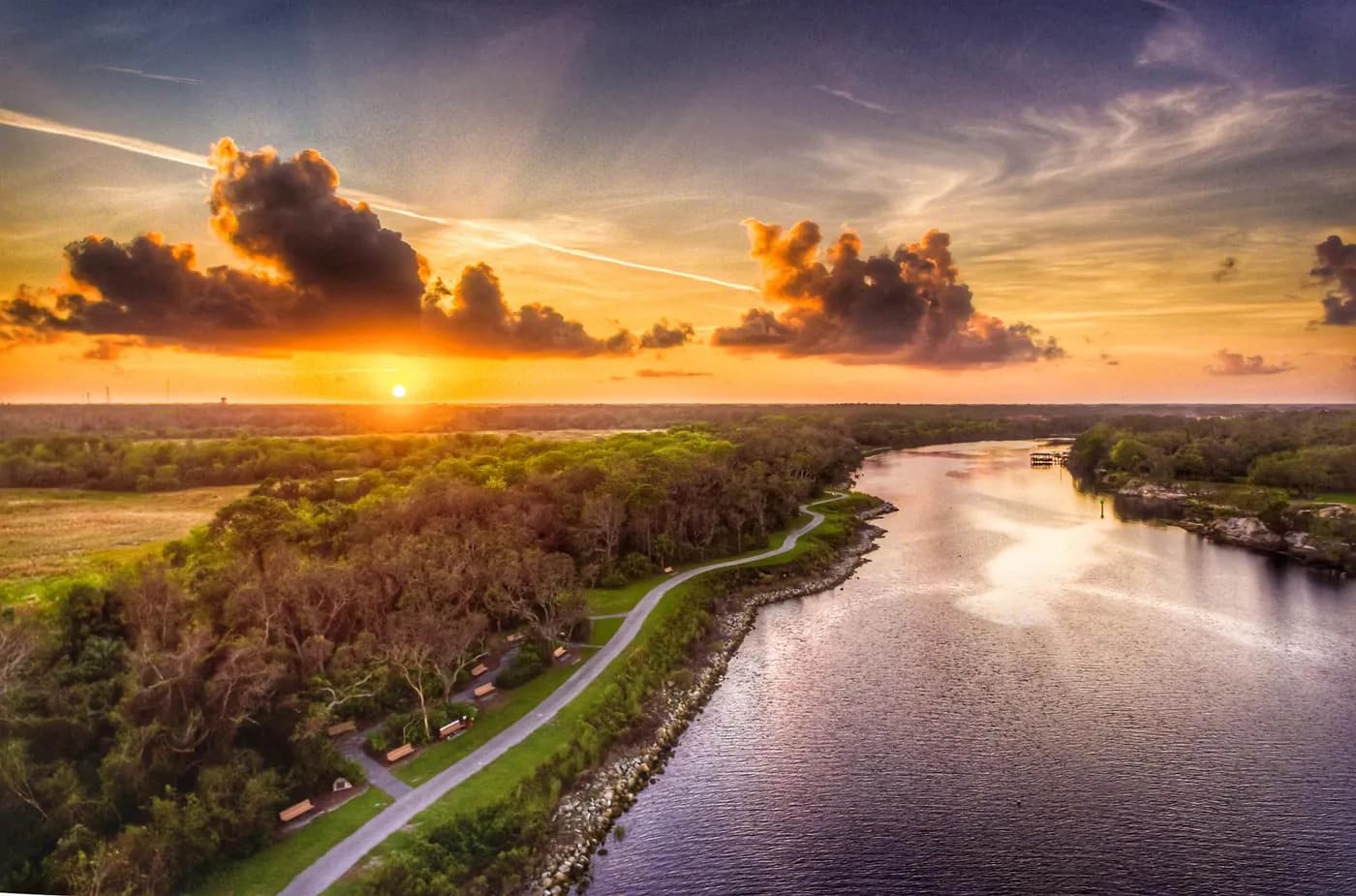 Sunset over a waterway, trees, and a winding path in Palm Coast